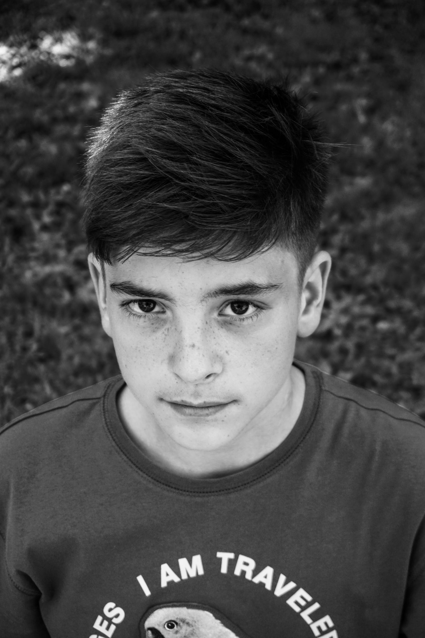 A close-up black and white portrait of a young boy with freckles, showcasing his intense gaze.