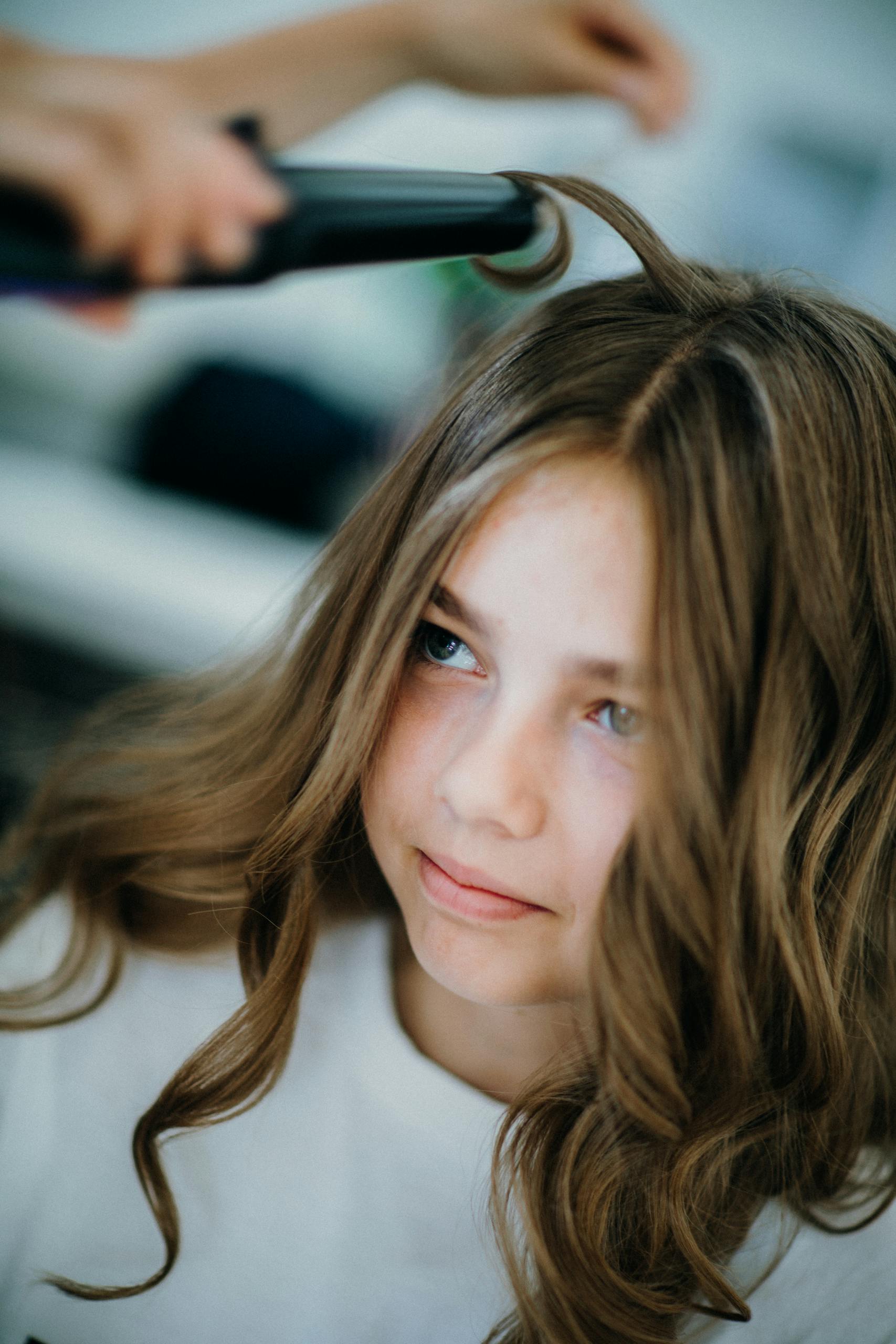 Close-up of a girl getting her hair curled at a salon, showcasing professional hairstyling.